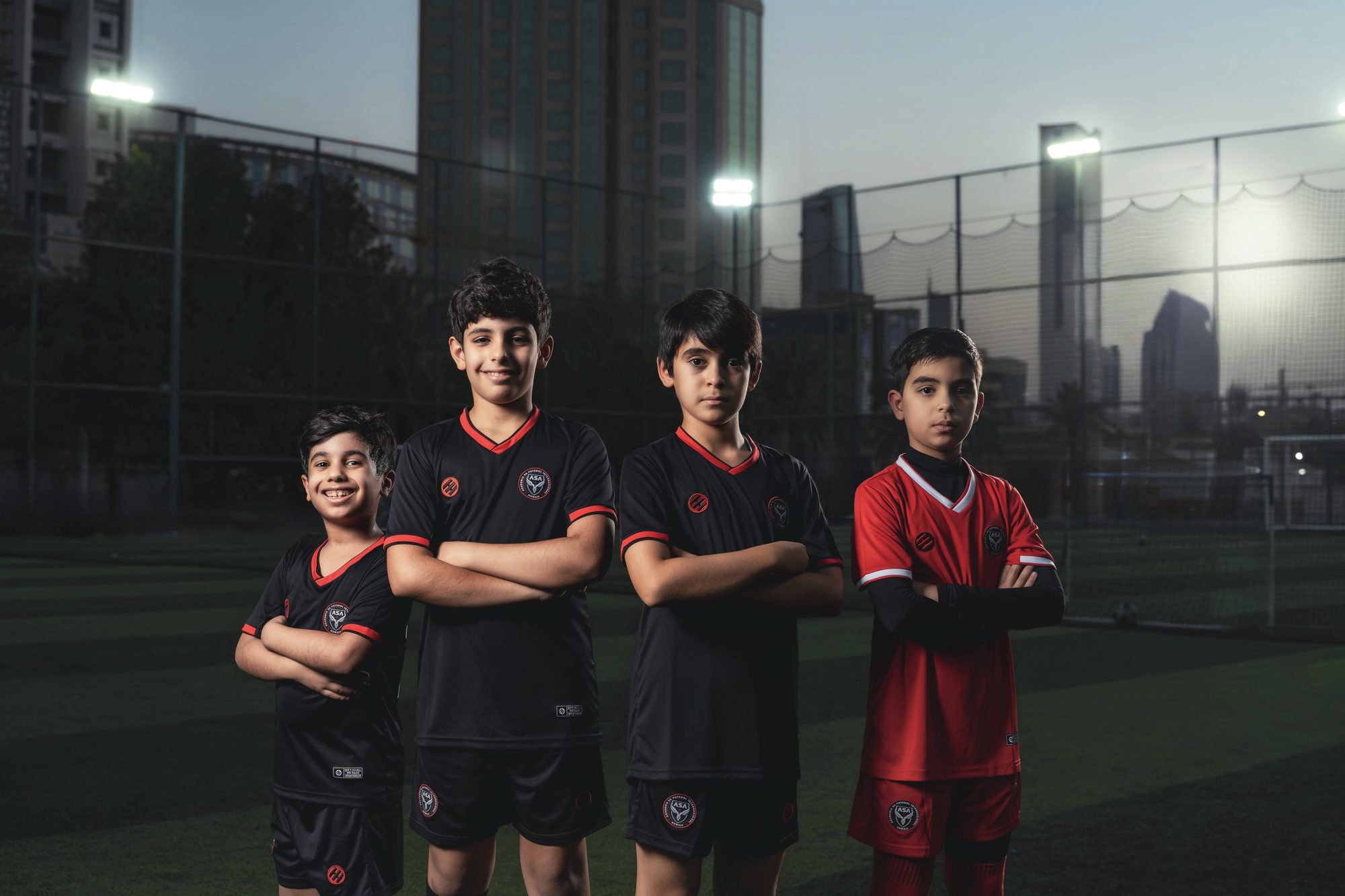 ASA players in black and red kits on the pitch at night